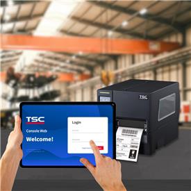 A hand holding a tablet displaying the TSC Web Console sign-in page. In the background, a TSC label printer sits in an industrial setting. A hand holding a tablet displaying the TSC Web Console sign-in page. In the background, a TSC label printer sits in an industrial setting.